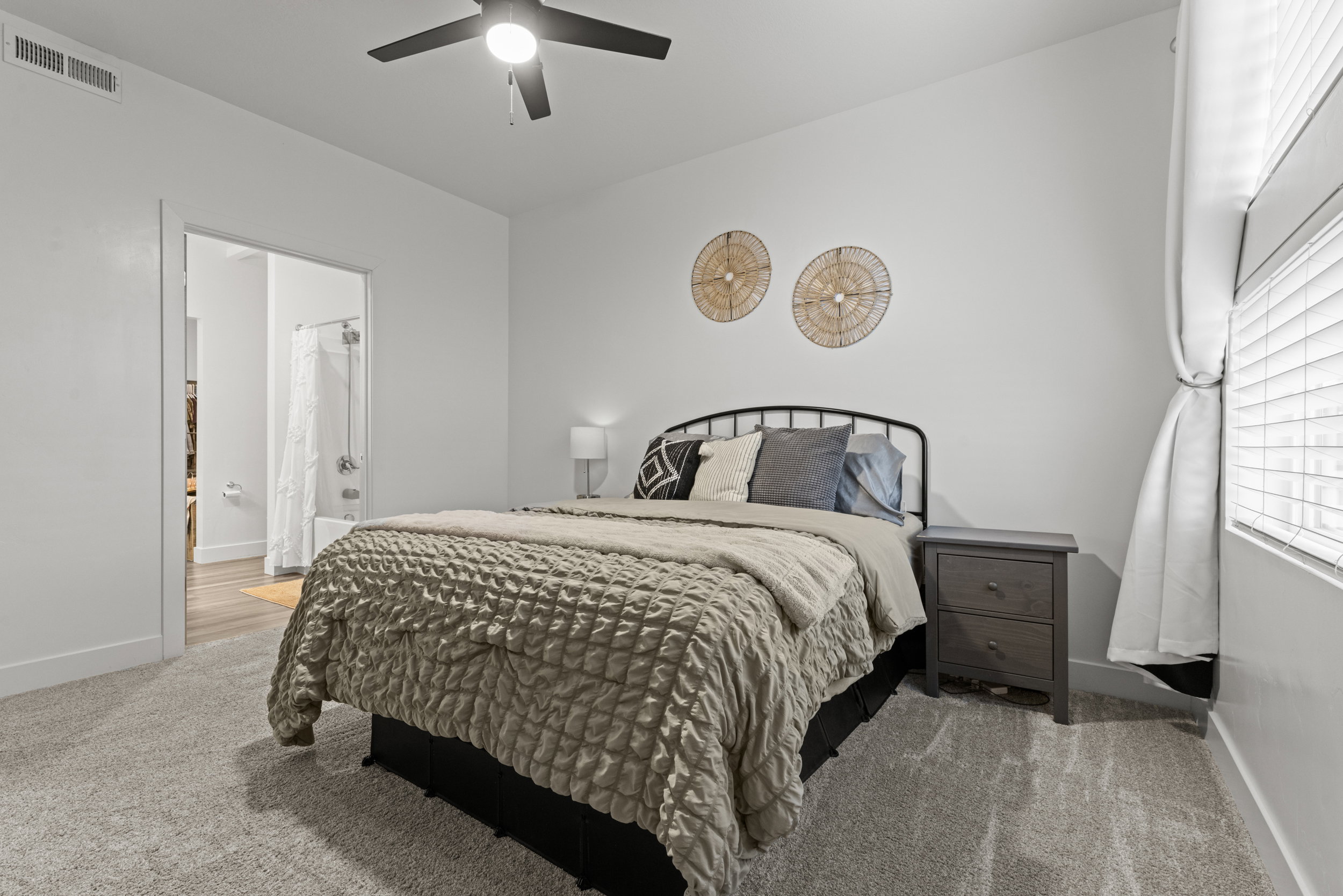 Bedroom with light colored carpet, ensuite bathroom, and ceiling fan