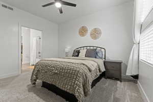 Bedroom with light colored carpet, ensuite bathroom, and ceiling fan