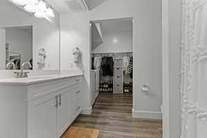 Bathroom with vanity, a spacious closet, dark wood finished floors, and curtained shower