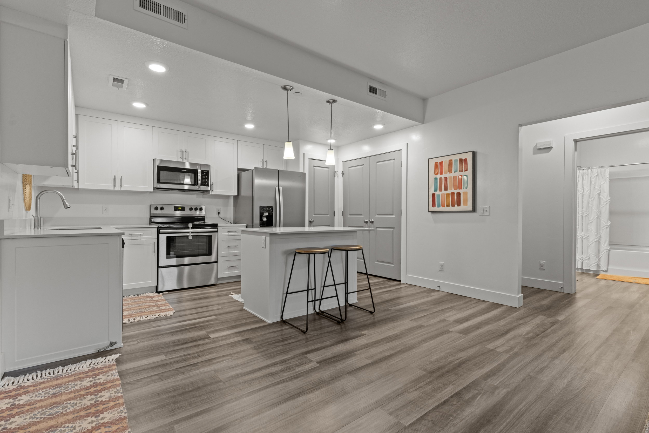 Kitchen with stainless steel appliances, a kitchen island, white cabinets, a kitchen breakfast bar, and light wood finished floors