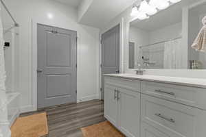 Full bathroom with vanity, dark wood-style flooring, and shower / bathtub combination with curtain
