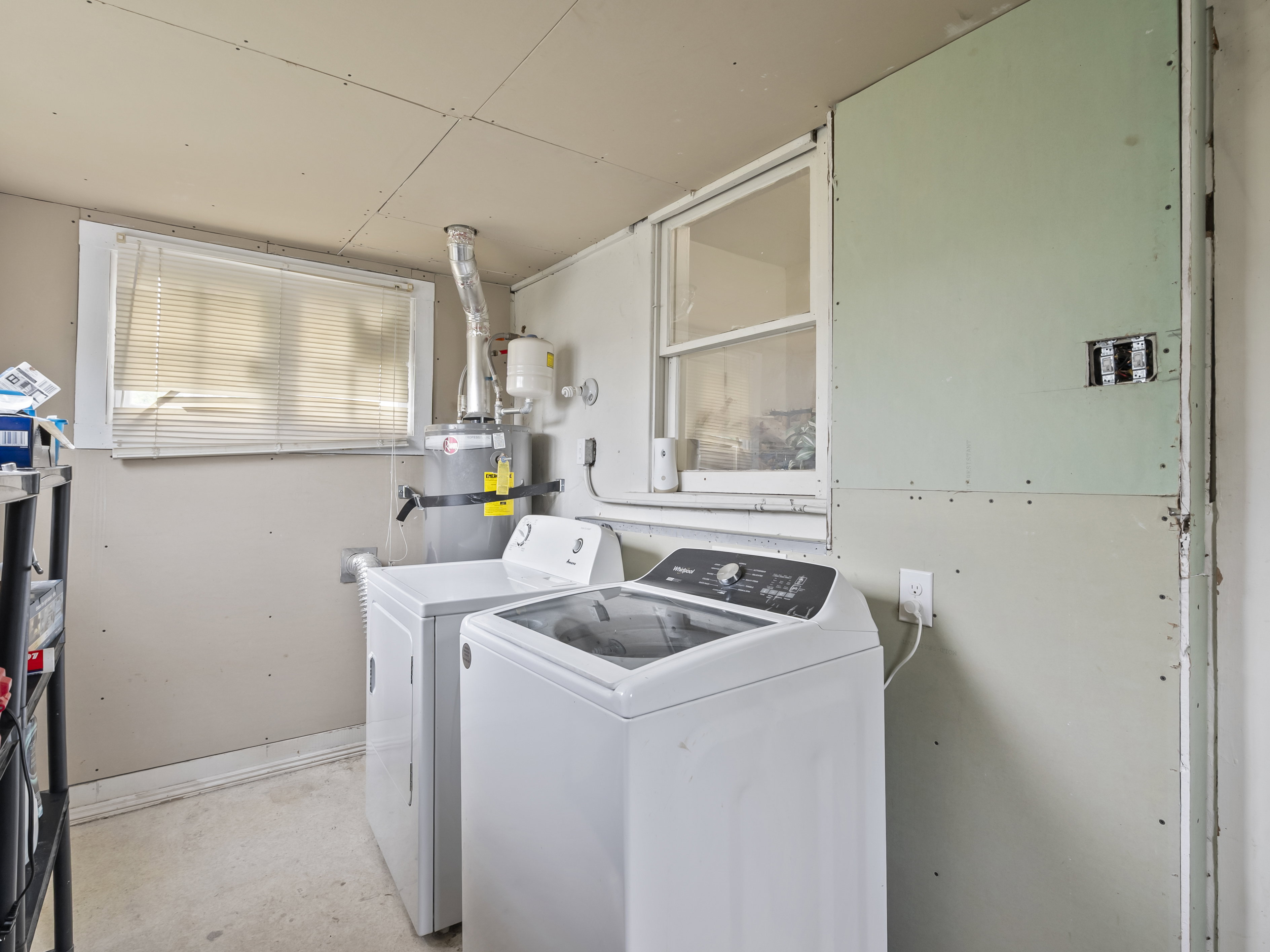 Laundry area featuring washing machine and clothes dryer, strapped water heater, and unfinished concrete floors