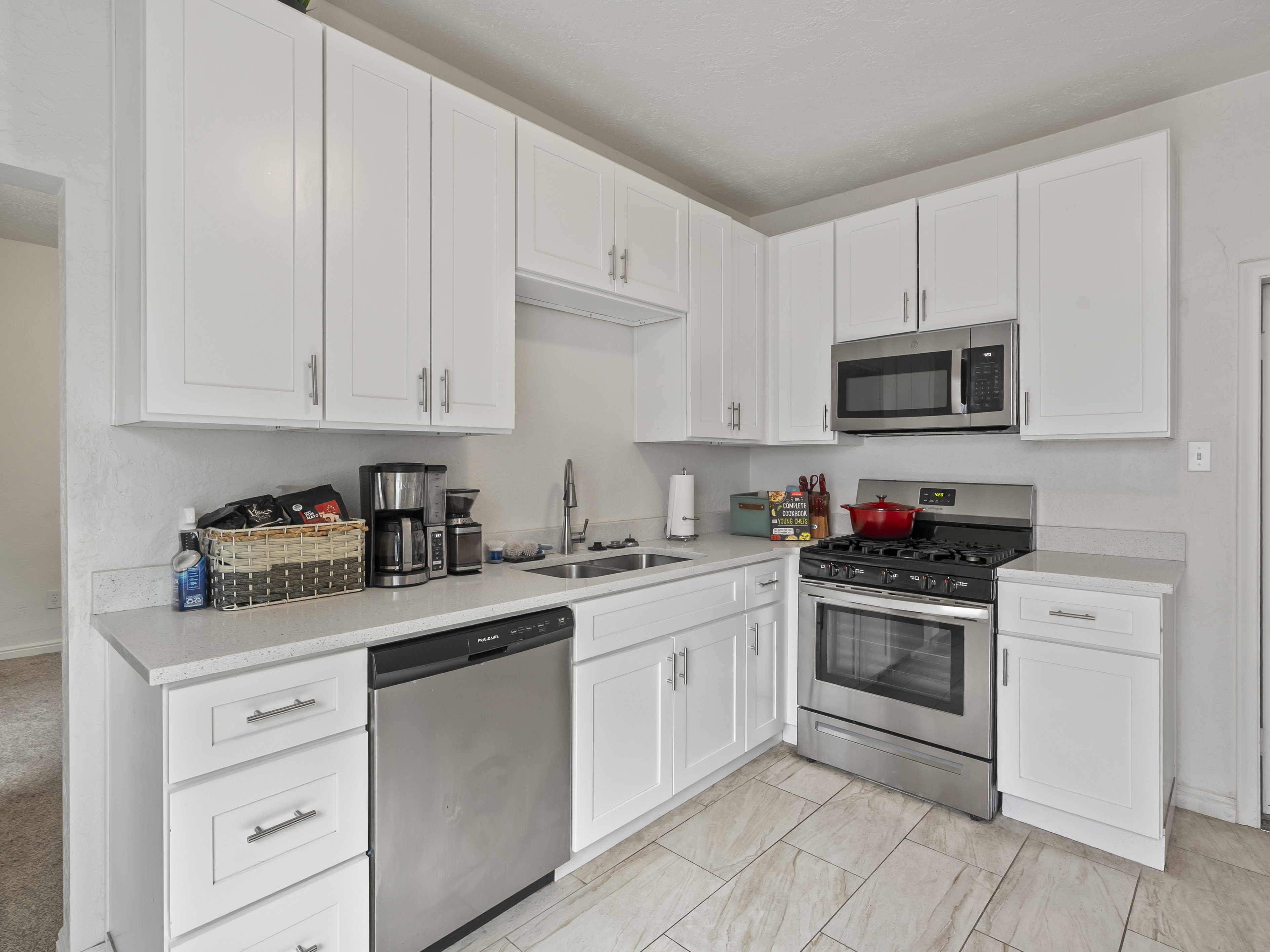 Kitchen with white cabinets, stainless steel appliances, and light stone counters