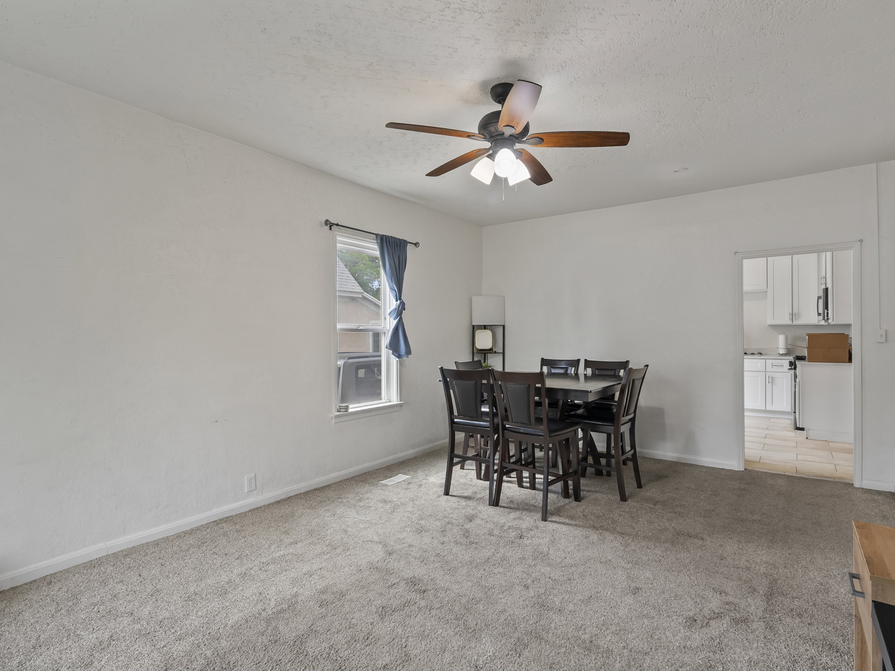 Dining room featuring light colored carpet, a ceiling fan, and a textured ceiling