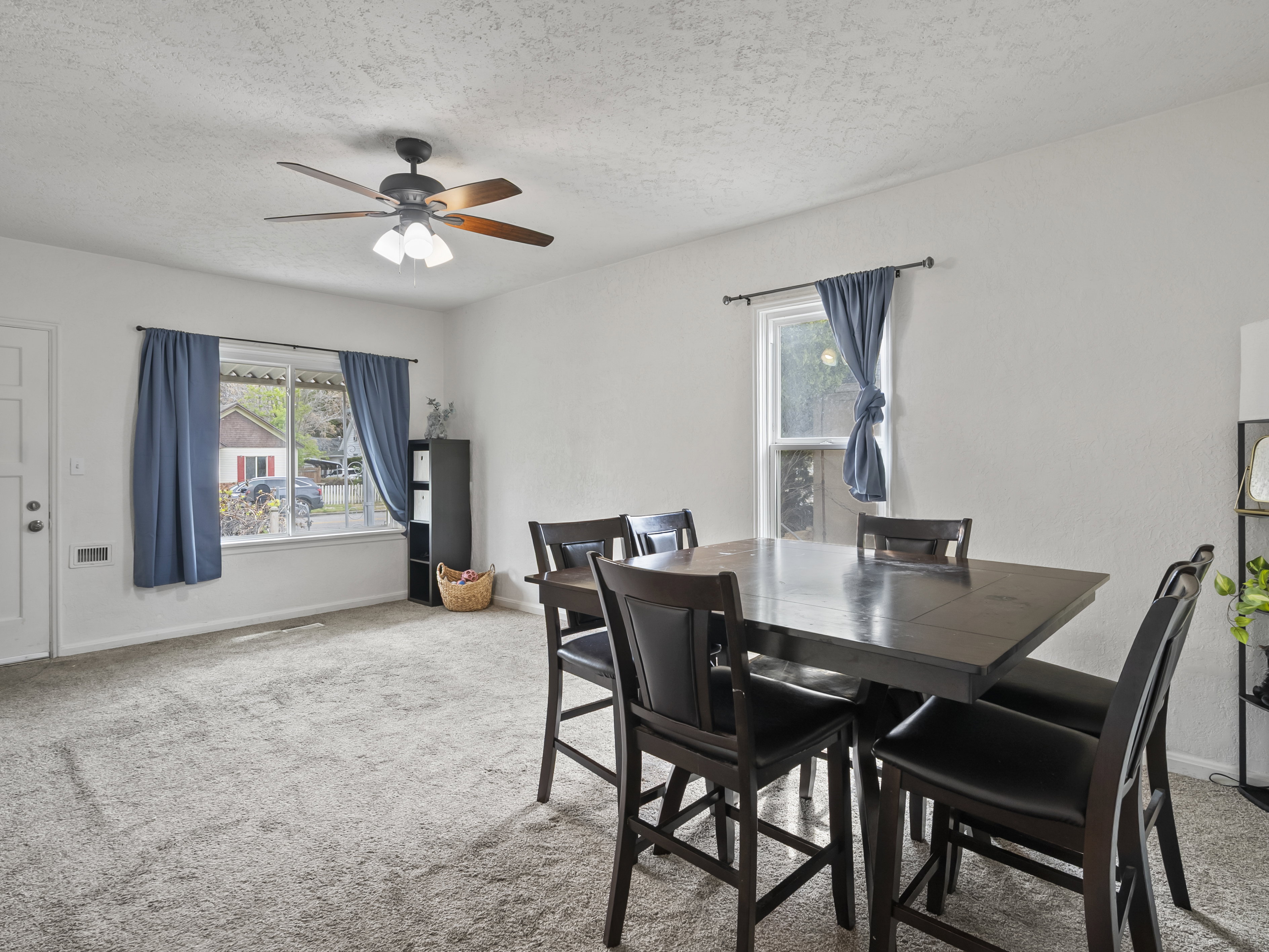 Dining room with light carpet, healthy amount of natural light, a ceiling fan, and a textured ceiling