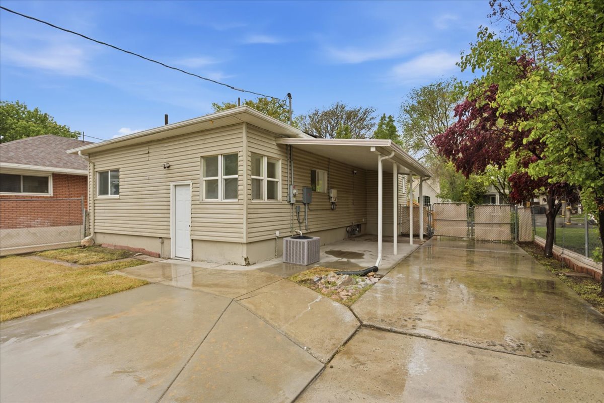 Rear view of house featuring a gate, concrete driveway, a patio, and a carport