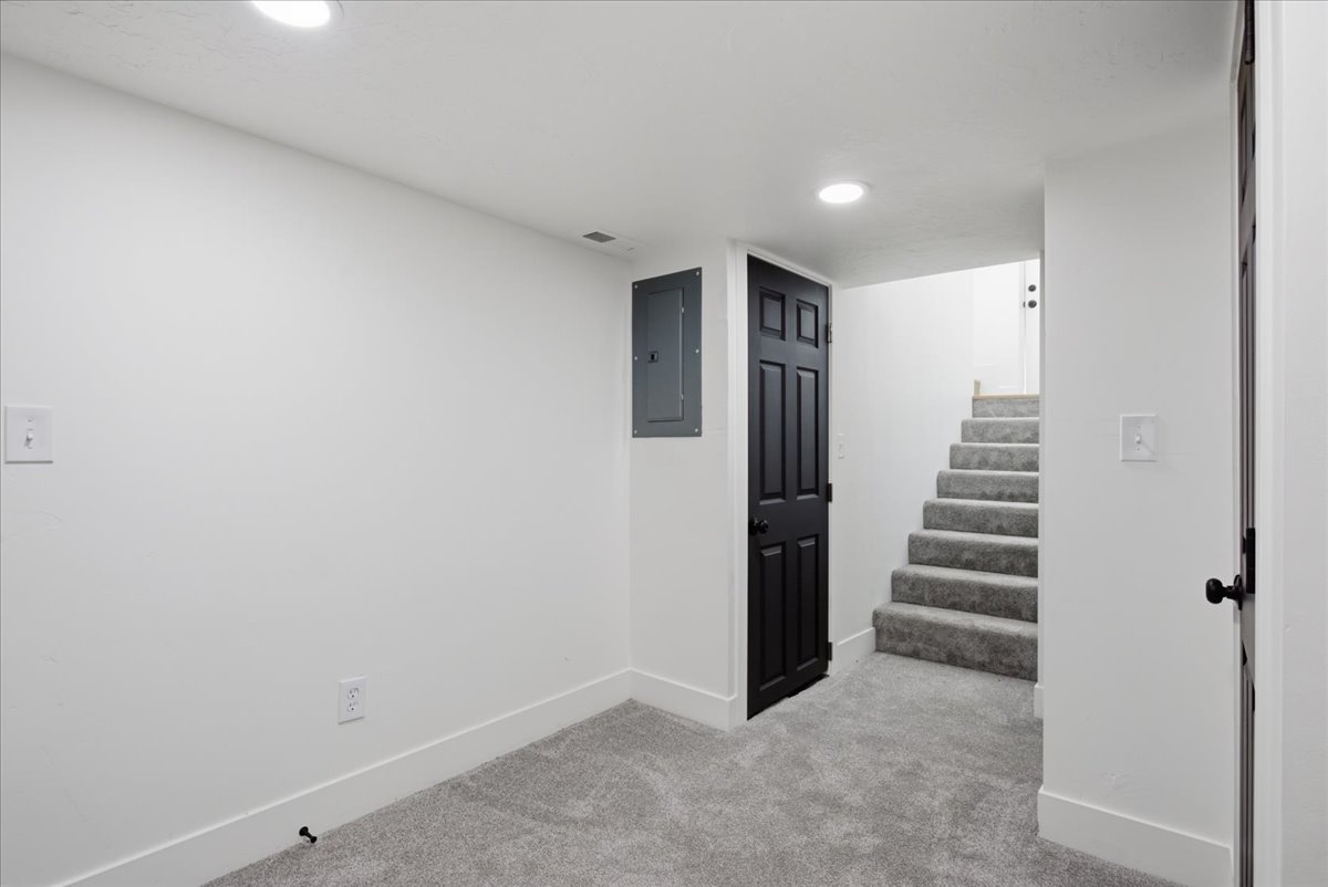 Finished below grade area with light colored carpet, electric panel, and recessed lighting