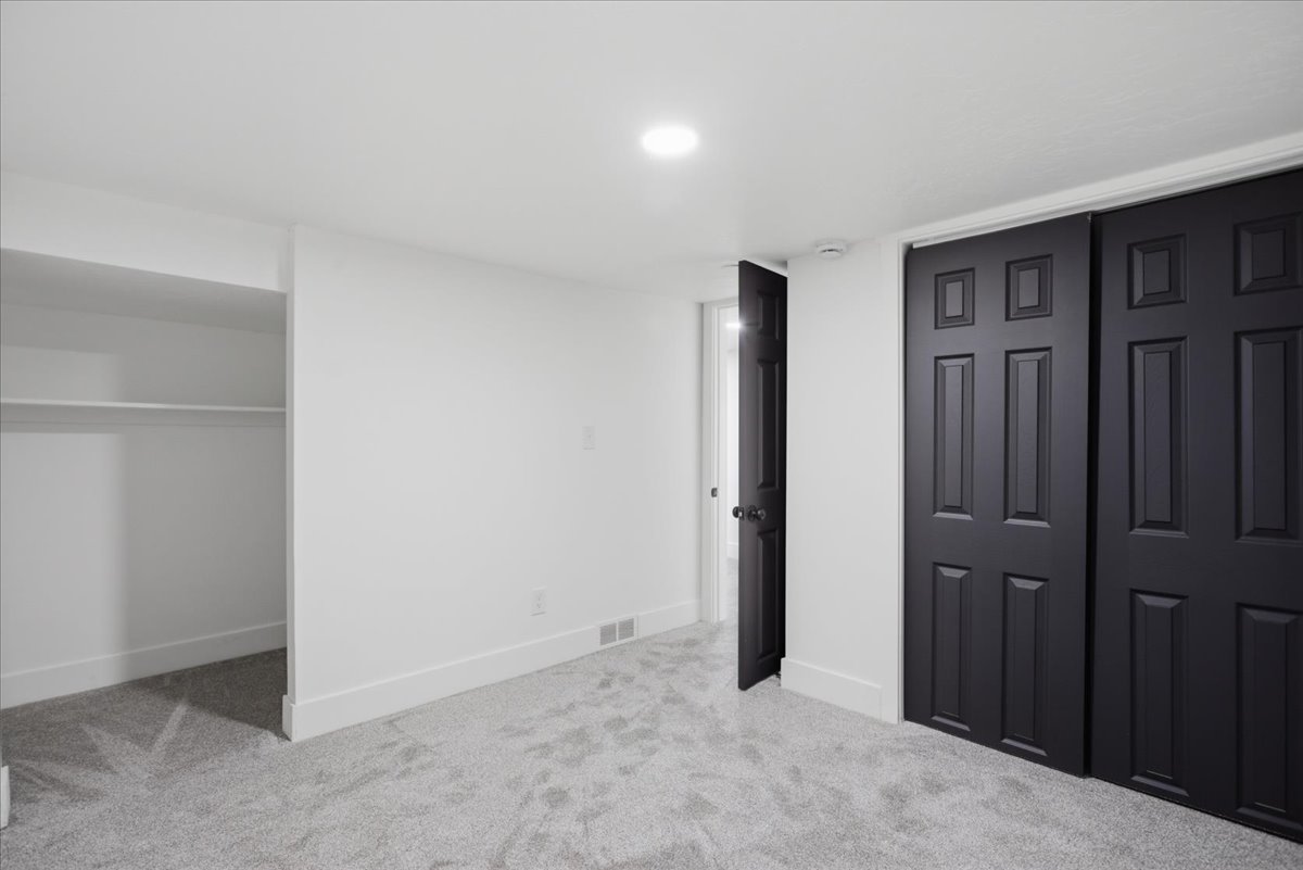 Unfurnished bedroom with light colored carpet and baseboards