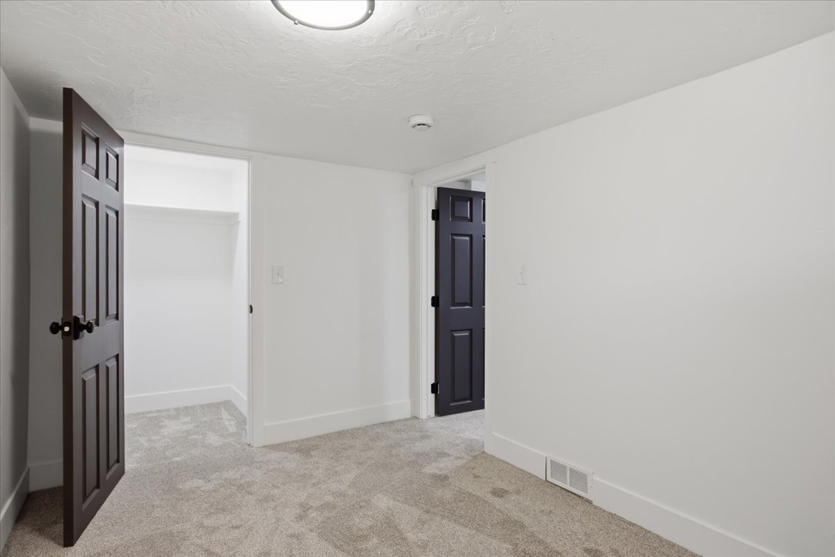 Unfurnished room featuring light carpet, a textured ceiling, and a smoke detector