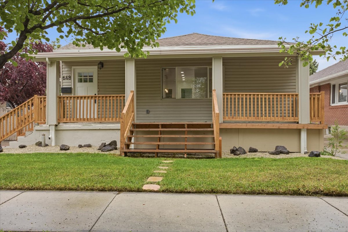 Ranch-style home with a shingled roof, covered porch, and a front lawn