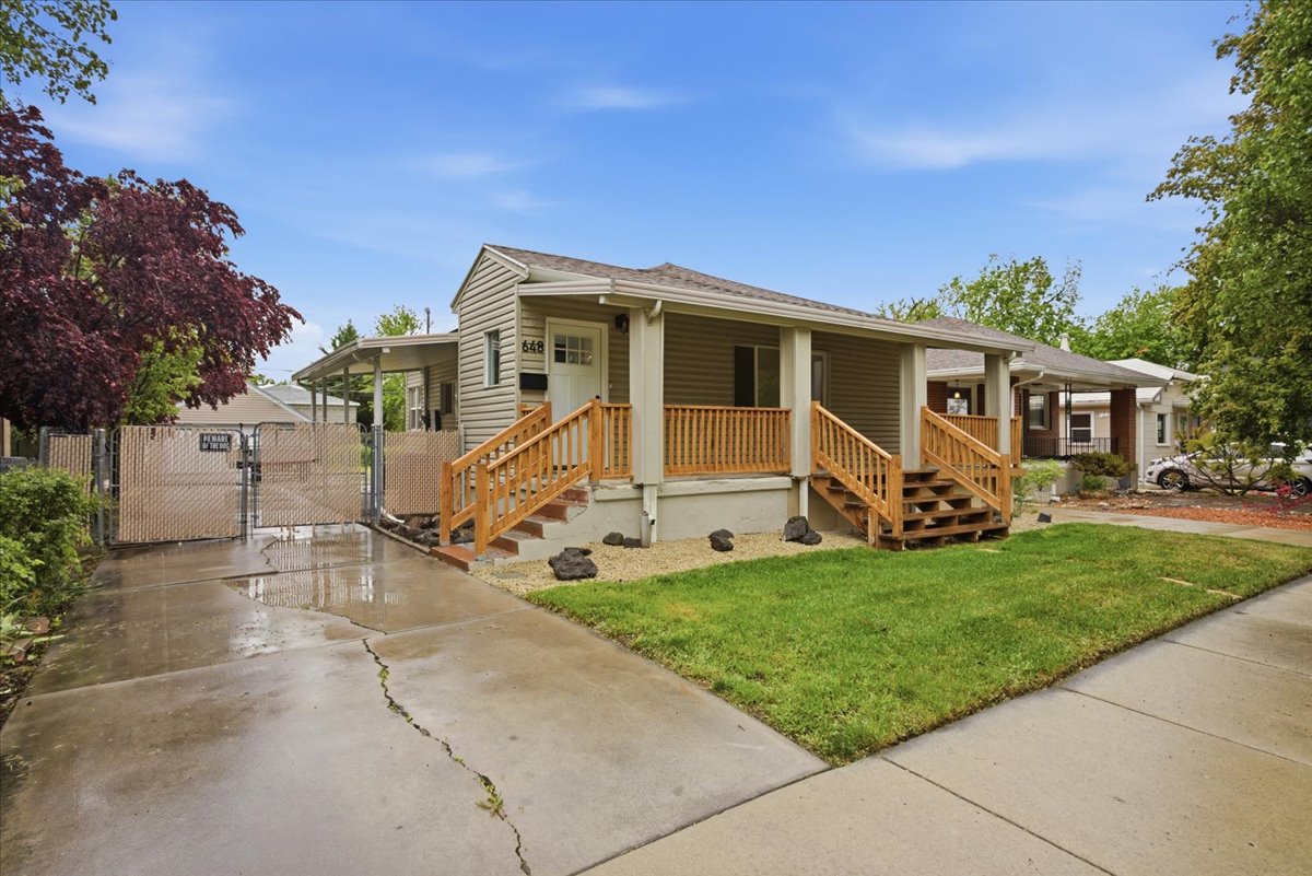 View of front of home featuring a gate, covered porch, a front lawn, and concrete driveway