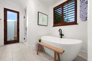 Full bath with a freestanding bath, a shower stall, and light tile patterned floors