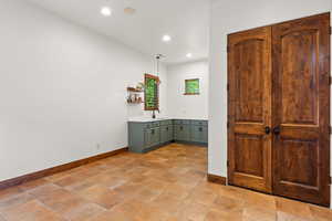 Bar featuring light countertops, open shelves, decorative light fixtures, and green cabinets