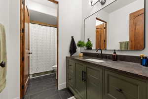 Bathroom with vanity, a shower with shower curtain, and dark marble finish floors