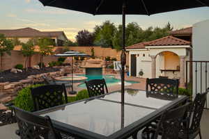 Fenced backyard with a patio area, outdoor dining space, a pool with connected hot tub, and a fireplace