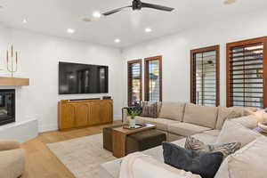 Living area with recessed lighting, light wood-type flooring, a glass covered fireplace, and ceiling fan