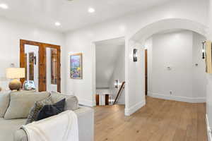 Living area with light wood-type flooring, recessed lighting, and arched walkways