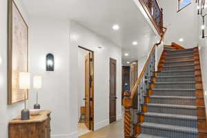 Stairway with wood finished floors and recessed lighting