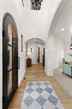 Foyer featuring arched walkways, light wood finished floors, and suspended lighting