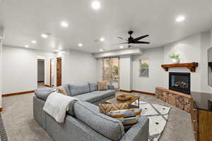 Carpeted living area featuring a ceiling fan, recessed lighting, and a glass covered fireplace