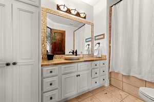 Full bathroom featuring vanity, light tile patterned floors, and a shower with shower curtain