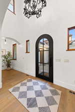 Entrance foyer with arched walkways, light wood-style floors, and a high ceiling