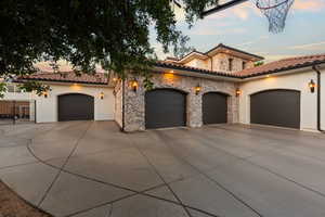 Mediterranean / spanish home featuring a garage, stone siding, concrete driveway, and stucco siding