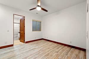 Unfurnished bedroom with light wood-style floors, ceiling fan, and connected bathroom