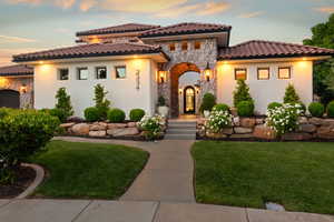 Mediterranean / spanish home with stone siding, a lawn, and stucco siding