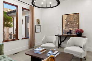 Sitting room featuring suspended lighting and carpet