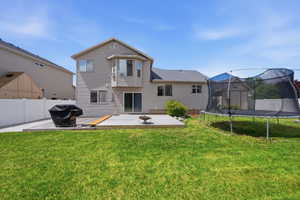 Back of house featuring a trampoline, a fenced backyard, and a deck
