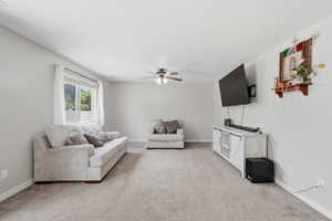 Living room featuring a ceiling fan and light colored carpet