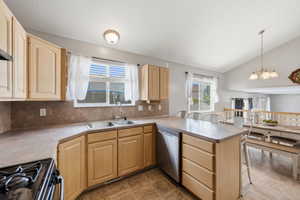 Kitchen featuring a peninsula, a kitchen bar, light wood finish cabinets, gas stove, and lofted ceiling