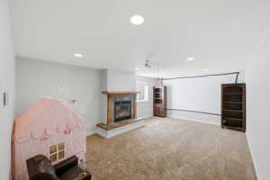 Unfurnished living room featuring a tiled fireplace, light carpet, and recessed lighting