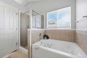 Bathroom featuring a stall shower, a jetted tub, and light tile patterned flooring