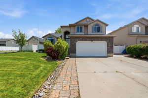 View of front of house featuring brick siding, driveway, an attached garage, and stucco siding