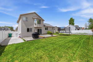 Rear view of property featuring a trampoline, a fenced backyard, and a patio area
