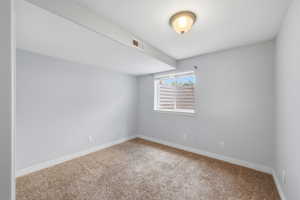Carpeted spare room featuring baseboards