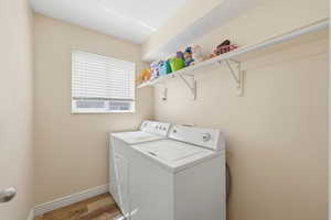 Laundry area featuring wood finished floors and washing machine and clothes dryer