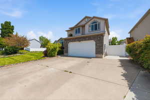 Traditional home with a gate, concrete driveway, brick siding, an attached garage, and stucco siding