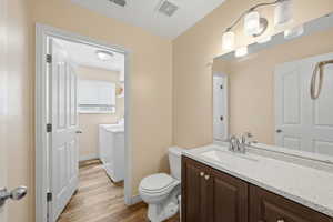 Bathroom with vanity, light wood-style floors, and washing machine and dryer