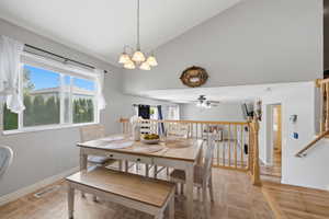 Dining space with vaulted ceiling, a chandelier, a ceiling fan, and light tile patterned floors