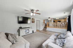 Living area with a ceiling fan and light carpet