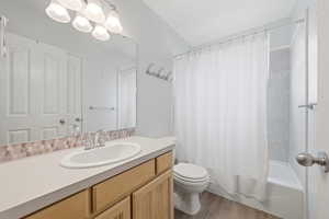 Bathroom featuring vanity, shower / bathtub combination with curtain, and light wood-type flooring