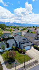 Two-story residence featuring a two-car garage, stone facade accents, and a landscaped front yard with a paved driveway
