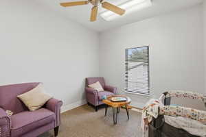 Living area with ceiling fan and light carpet