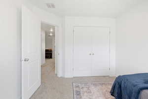 Bedroom featuring light carpet and a closet