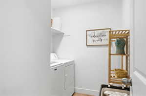 Laundry room with light wood-style flooring and washing machine and dryer