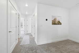 Corridor with baseboards and light carpet