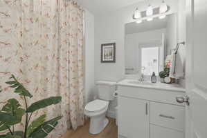 Bathroom featuring curtained shower, vanity, and light wood-style flooring